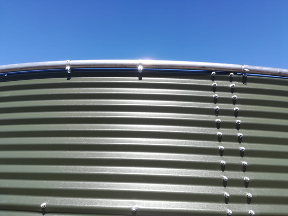 Large metal water tanks with blue lids at an industrial site.
