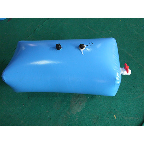A blue, rectangular inflatable water bladder with two black caps on top and a white valve with a red cap on the side lies on a green surface, filled with water.