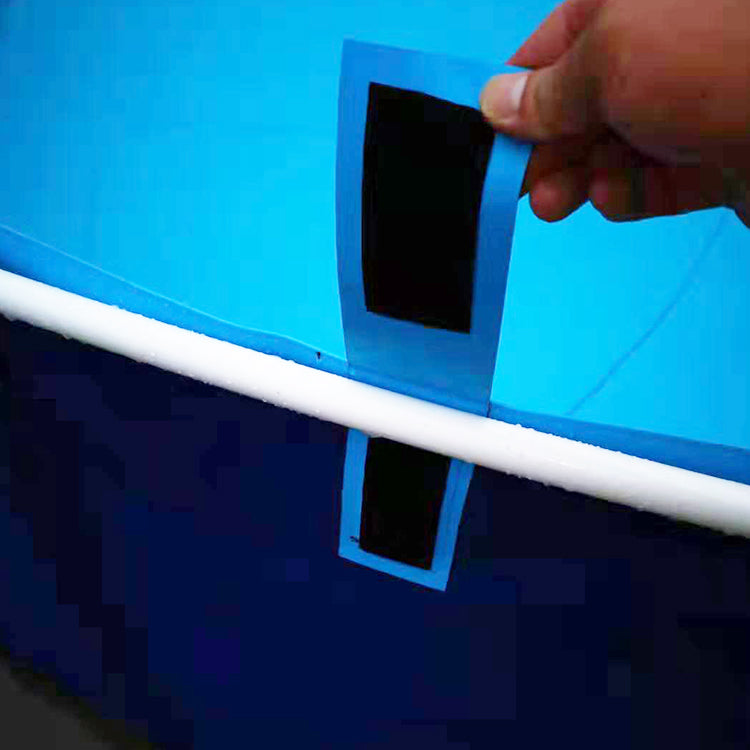A hand holds a black rectangular patch with a blue backing over a blue above-ground pool, preparing to apply it near the white frame with connecting pipes, while the pool is filled with water.
