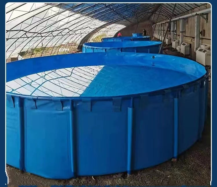 Large blue collapsible fish water tank filled with water in a greenhouse, with additional tanks in the background, suitable for aquaculture or industrial water storage.