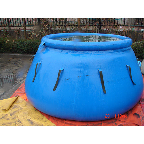 Large blue inflatable water storage bladder filled with water, featuring black straps, placed on a yellow and orange surface outdoors, perfect for emergency water storage or agricultural use.
