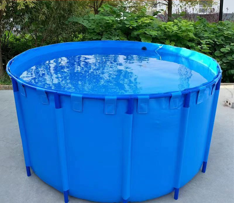 Blue circular collapsible fish water tank filled with water, placed on a concrete surface with greenery in the background, ideal for portable water storage in outdoor settings.