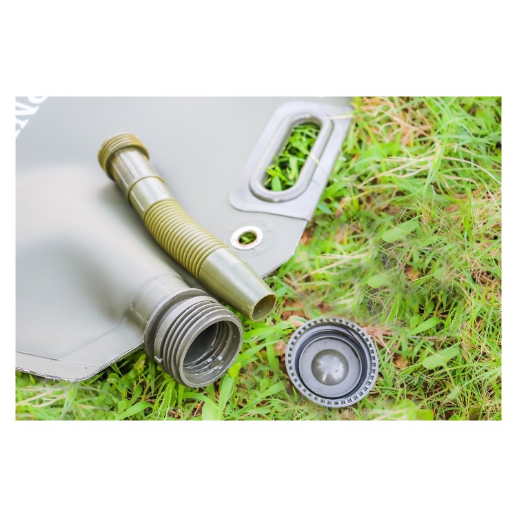 A gray fuel tank with a corrugated hose and a black cap rests on a grassy surface. The tank has a handle for easy carrying, and the hose is attached to the cap, which features a secure, threaded design.